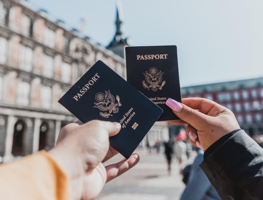 Two people holding U.S. passports in a public square